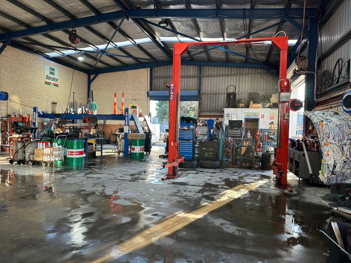 Inside the Tanilba Bay Automotive workshop with vehicle hoists and Castrol oil drums